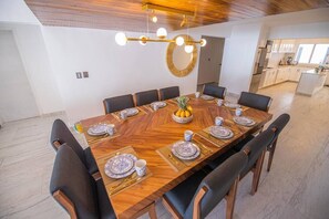 A dining area with a large wooden table set for a meal, surrounded by chairs.