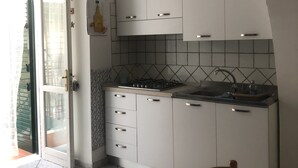 Une cuisine avec des meubles blancs, un dosseret carrelé, une cuisinière à gaz et un évier.