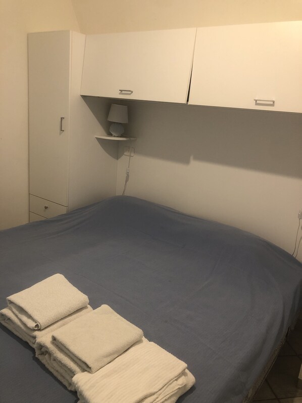 Une chambre avec un lit, une armoire et une table de chevet avec une lampe.