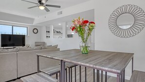 Un salon moderne comprenant un coin repas, un ventilateur de plafond, un téléviseur à écran plat et un vase de fleurs.