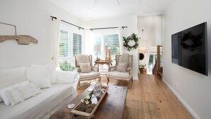 A living room with a sofa, two armchairs, a coffee table, and a TV mounted on the wall. - Sunny Corner - Romantic Split Level Cottage (Leura)