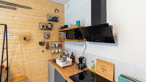 A compact kitchen with wooden walls, a black range hood, and various kitchen appliances. - HAPPY HOME HELSINKI-KALLIO (Helsinki)