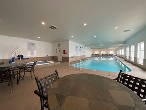Piscina interna com banheira de hidromassagem, área de estar e regras do spa afixadas nas paredes.