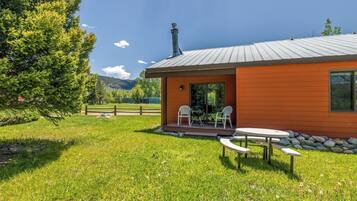 A wooden cabin with a metal roof, a chimney, and a patio with outdoor seating.