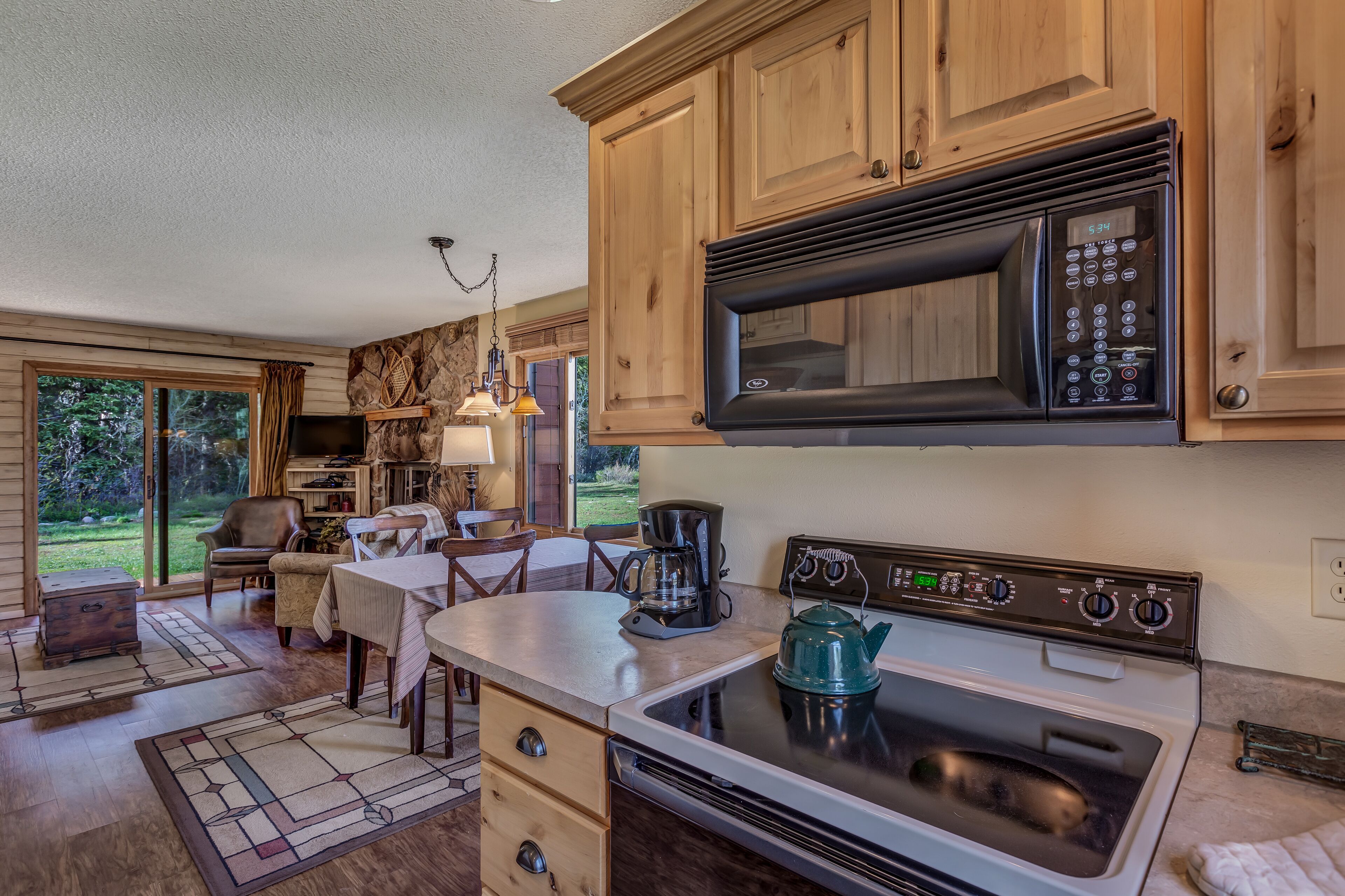 A kitchen with wooden cabinets, a microwave, an oven, and a coffee maker.