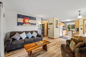 A living room with a sofa, coffee table, and a painting on the wall.