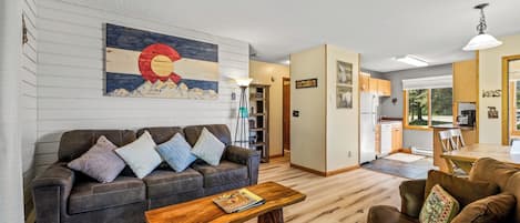 Een woonkamer met een bank, salontafel en een schilderij aan de muur.