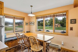 A kitchen with a wooden table and chairs, large windows, and a view of the outdoors. - Honey Bear - Mountain cabin with gorgeous scenery (Clark)