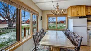 A dining area with a large table and chairs, wooden cabinets, and a chandelier.