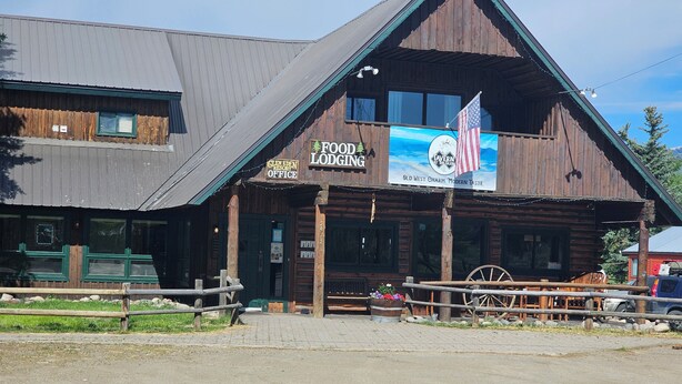 Un edificio rústico de madera con un letrero que dice 'Comida, Alojamiento' y 'Oficina del Resort Glen Eden'.