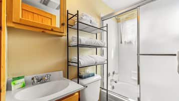 A bathroom with a white sink, a wooden cabinet, a towel rack, and a glass shower enclosure.