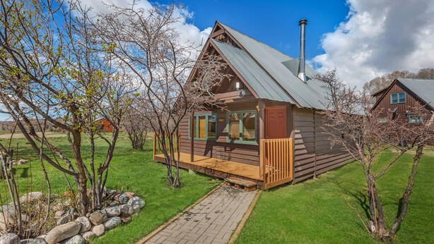 A wooden cabin with a porch, a chimney, and a stone pathway leading to it.