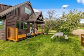 Une cabane en bois avec un porche, un espace salon extérieur et un barbecue.
