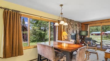 A dining area with a wooden table and chairs, a stone wall, and a television.