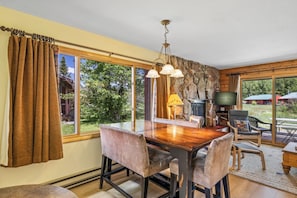 A dining area with a wooden table and chairs, a stone wall, and a television. - Indian- Full kitchen, pet friendly, stunning views (Clark)