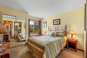 A bedroom with a large bed, a bedside table with a lamp, a mirror, and a window with curtains. - Indian- Full kitchen, pet friendly, stunning views (Clark)