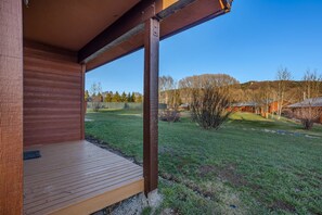 A wooden deck with a view of a grassy yard and distant trees. - Independence - Cozy cabin, pet friendly, hot tub (Clark)