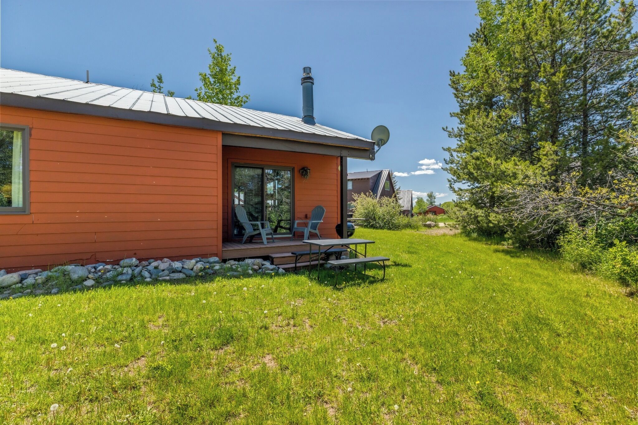 A single-story house with a sloped roof, a satellite dish, and a patio with outdoor furniture.