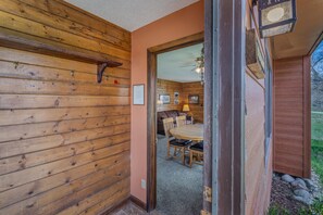 A wooden interior with a dining area, a ceiling fan, and a view through an open door.
