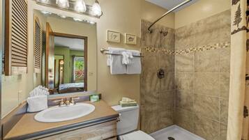 Une salle de bain équipée d’un lavabo, de toilettes, d’une douche et d’un miroir avec éclairage.