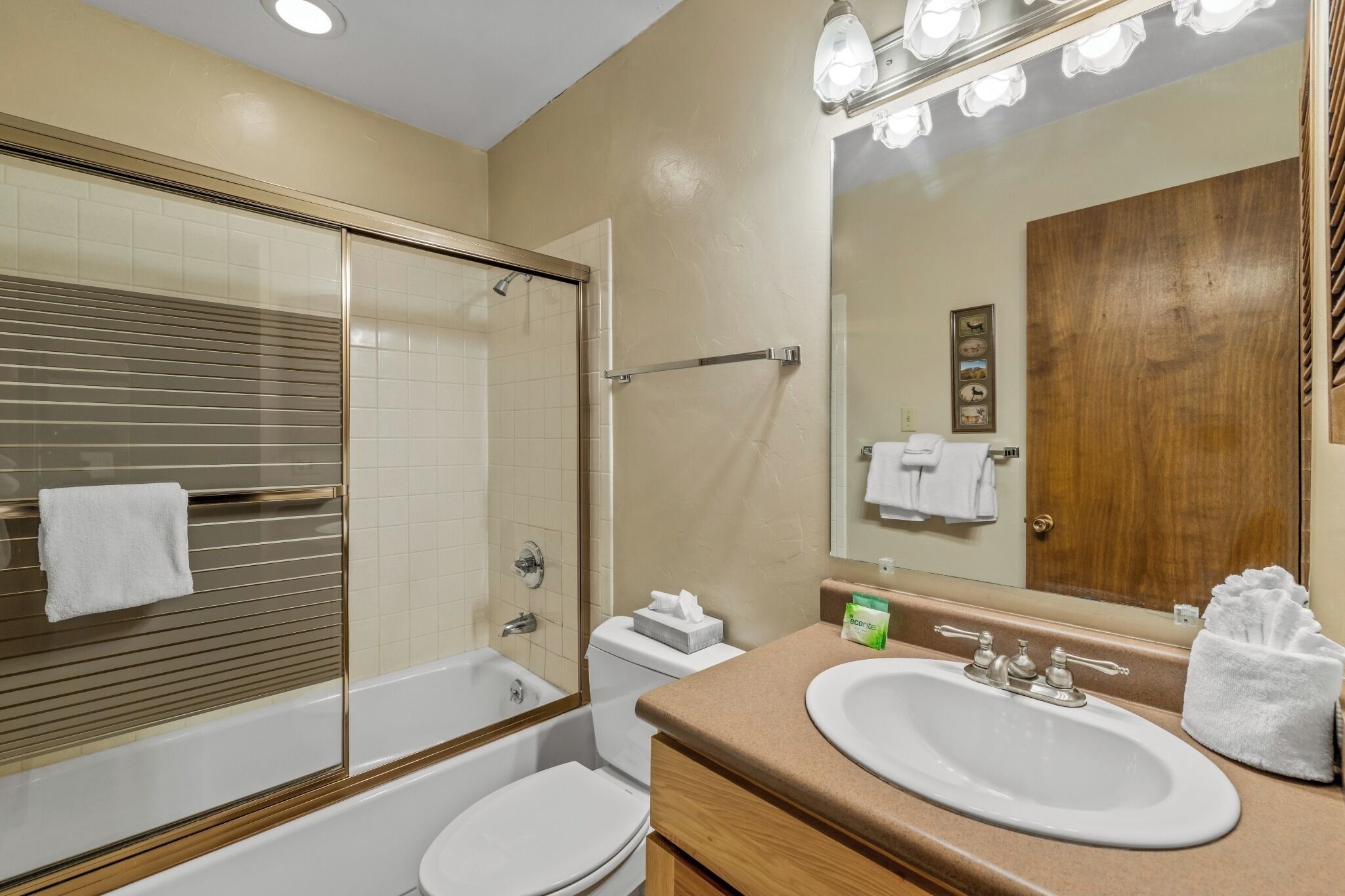 A bathroom with a bathtub, toilet, sink, and a large mirror.