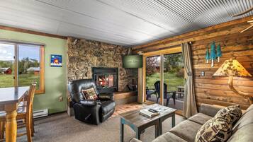 A cozy living room with a stone wall, leather sofa, and a fireplace.