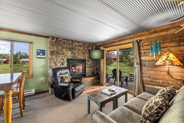 A cozy living room with a stone wall, leather sofa, and a fireplace.