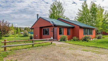 A red building with a metal roof, a satellite dish, and a gravel driveway.