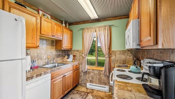 A kitchen with wooden cabinets, a white refrigerator, a sink, a stove, and a window with curtains.