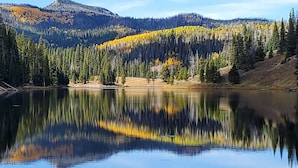 A calm lake reflecting trees and a mountain. - Mustang - Escape to the wilderness (Clark)