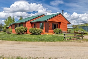 A single-story building with a green roof, surrounded by well-maintained grass and a wooden fence. - Mustang - Escape to the wilderness (Clark)