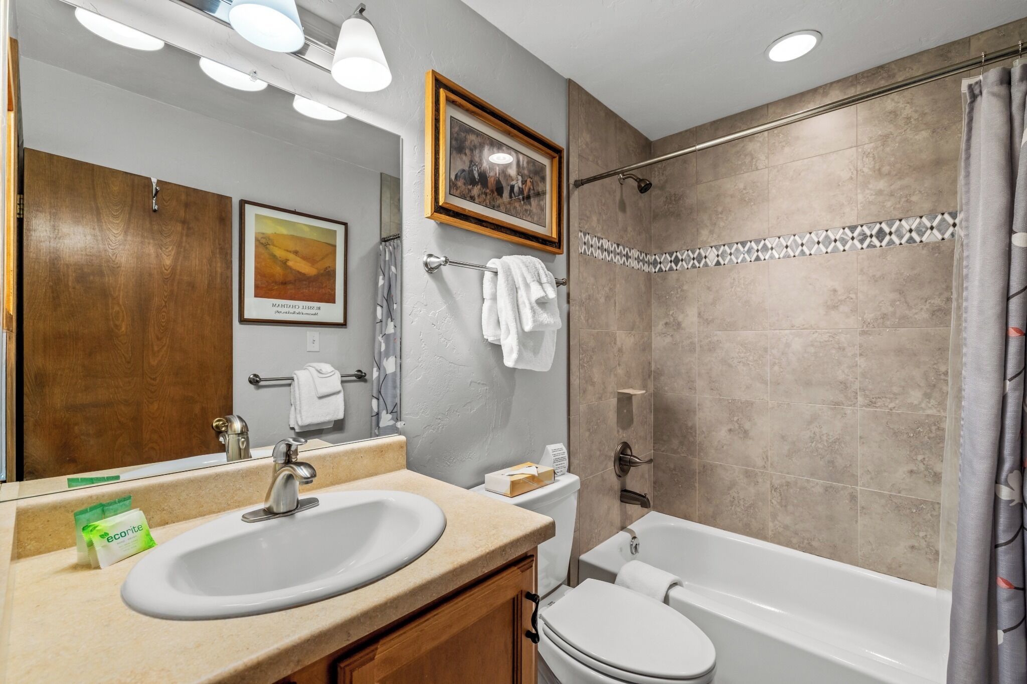 A bathroom with a sink, toilet, and bathtub. There are towels hanging on the wall and a shower curtain.