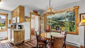 A kitchen with wooden cabinets, a dining table with chairs, and a chandelier. - Riverhouse - Fireplace, kitchen, pet friendly! (Clark)