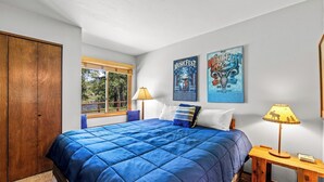 A bedroom with a large bed, wooden wardrobe, window with view, two wall art pieces, and bedside lamps. - Riverhouse - Fireplace, kitchen, pet friendly! (Clark)
