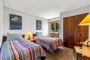 Una camera da letto con due letti, una finestra, un armadio in legno e poster alle pareti.