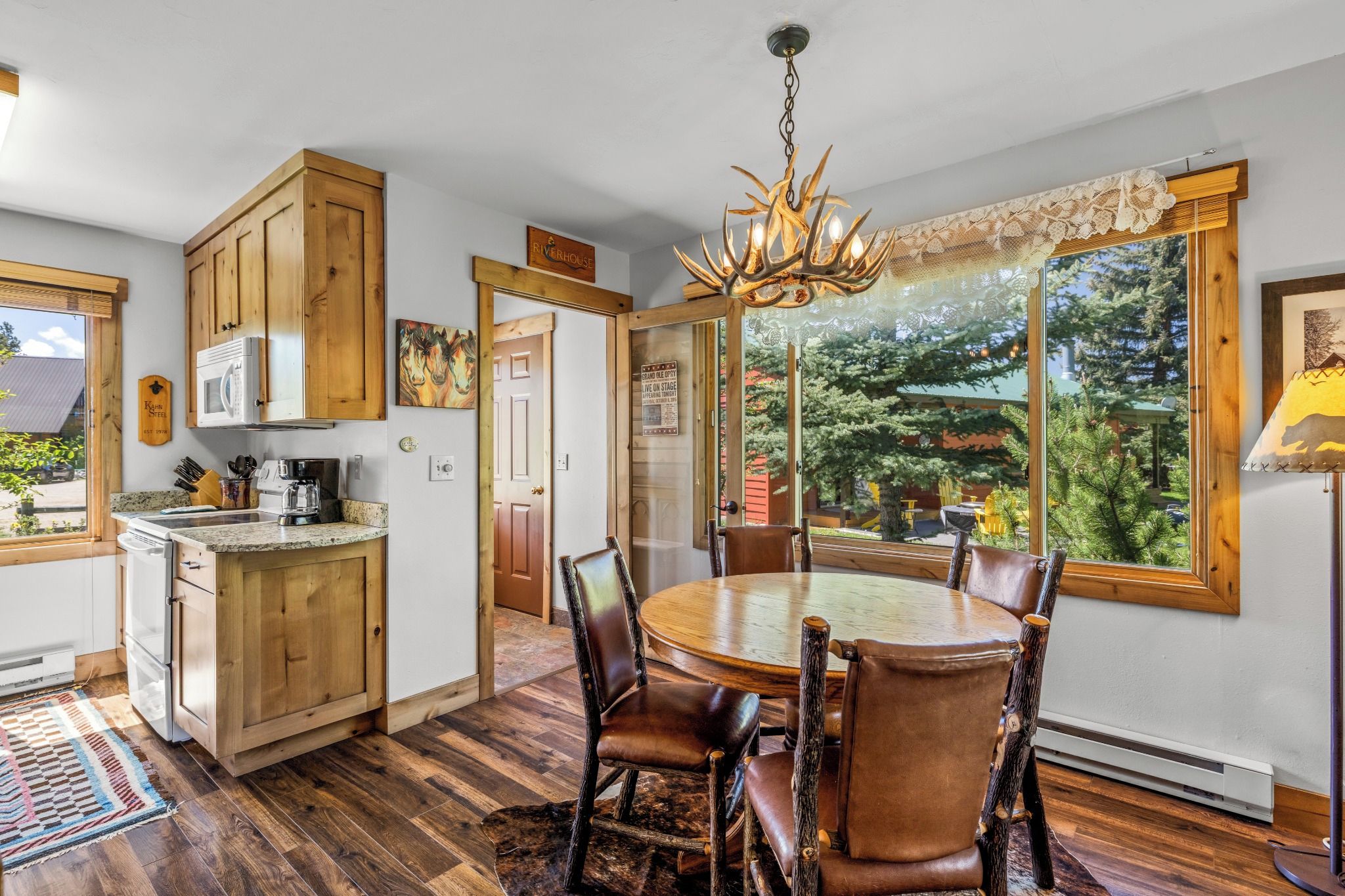 Une cuisine avec des meubles de rangement en bois, une table à manger avec des chaises et un lustre.