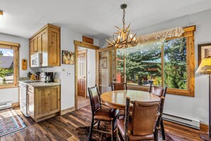 A kitchen with wooden cabinets, a dining table with chairs, and a chandelier. - Riverhouse - Fireplace, kitchen, pet friendly! (Clark)