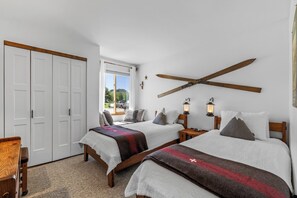 Ein Schlafzimmer mit zwei Betten, einem Holzbalken an der Decke und Blick ins Freie.