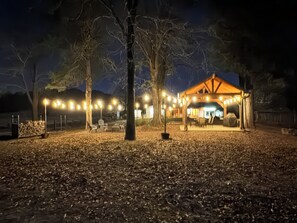 A gazebo with string lights, surrounded by trees and a leaf-covered ground. - Littlecreek: Secluded Cabin + 40 Acres All to Yourself + Pond (Avinger)