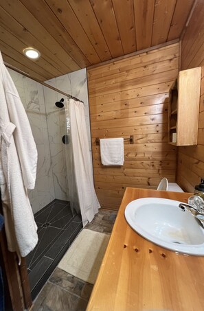 Bathroom features a shower area with a glass door, a vanity with a sink and mirror, and a tiled floor.