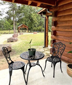 Relax in this serene outdoor space with a potted plant on a small table, surrounded by a well-maintained lawn and a wooden gazebo.