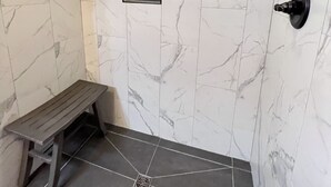 A shower area with a bench, a small window, and a showerhead. - Littlecreek: Rustic cabin get away. (Avinger)