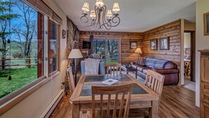 L’intérieur d’un chalet confortable, avec une table à manger, des chaises, un lustre et un canapé.