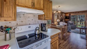 Une cuisine avec des meubles de rangement en bois, une cuisinière et un coin repas comprenant une table et des chaises.