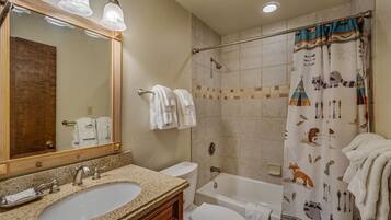 A bathroom with a sink, toilet, bathtub, and shower curtain with animal prints.