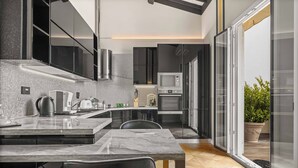 A modern kitchen with a marble countertop, stainless steel appliances, and a view of the outdoors.
