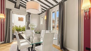 A dining area with a glass table, white chairs, and a vase of flowers.