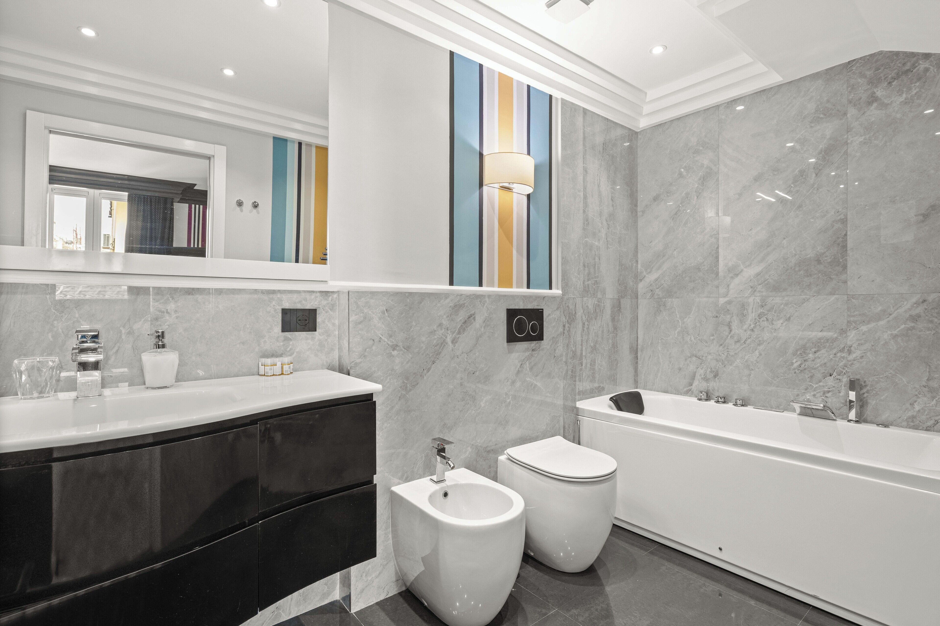 A modern bathroom with a large bathtub, a bidet, and a toilet.