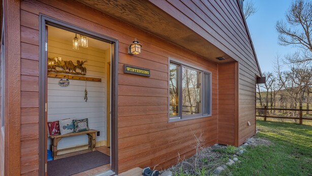 Une cabane en bois avec un banc à l’extérieur, un paillasson et une pancarte sur laquelle on peut lire « WINTERSONG ».