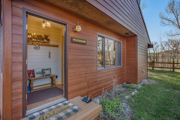 A wooden cabin with a bench outside, a welcome mat, and a sign reading "WINTERSONG".